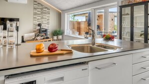 Een moderne keuken met een groot kookeiland, roestvrijstalen apparatuur en een wand met een stenen accent.
