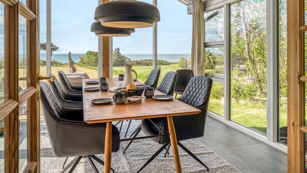 Een eetgedeelte met een grote tafel, zwarte stoelen en een hanglamp.