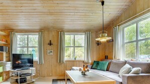 A cozy cabin-style room with a wooden interior, a television, a sofa, and a dining table.