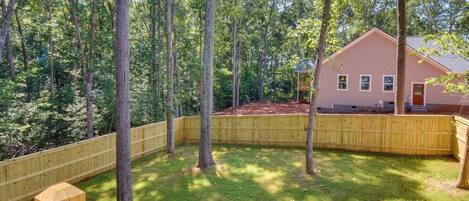 A backyard with a wooden fence, a house, and trees.