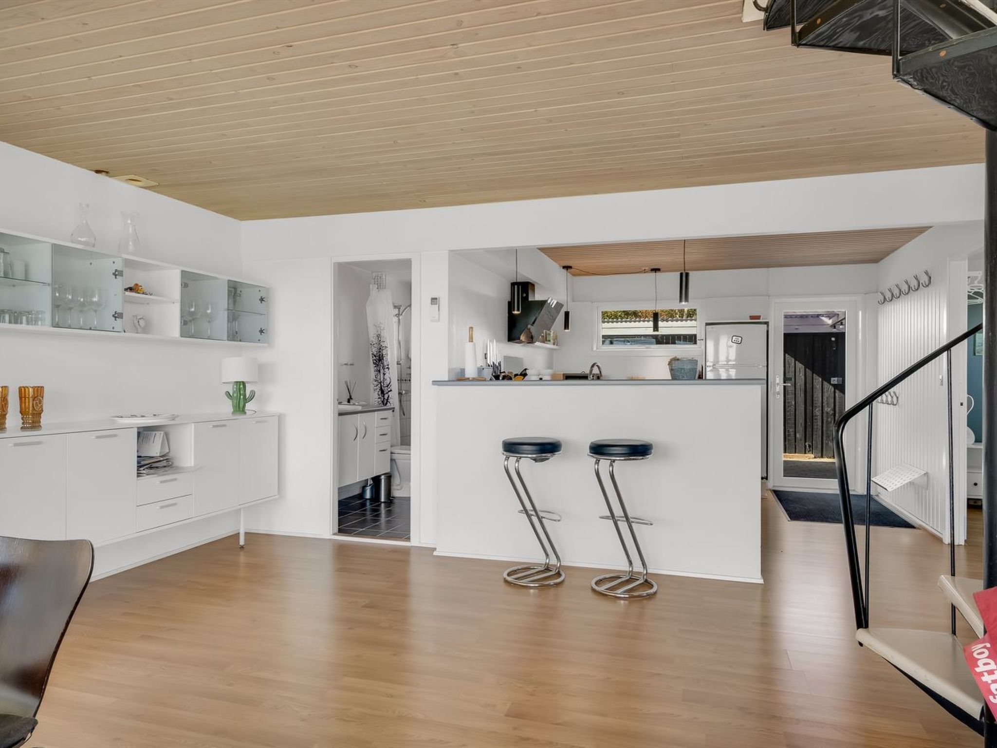 Une cuisine moderne avec des meubles blancs, un îlot central et deux tabourets de bar.