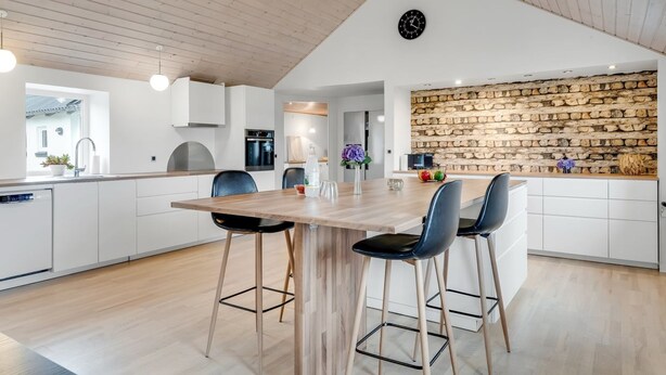 Een moderne keuken met een houten plafond, witte kasten en een backsplash van natuursteen.