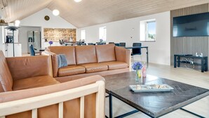 Een ruime woonkamer met een leren bank, een salontafel en een eethoek met stoelen en een tafel.