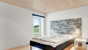 Een moderne slaapkamer met een groot bed, uitzicht op de omgeving en een unieke wand met een bakstenen patroon.