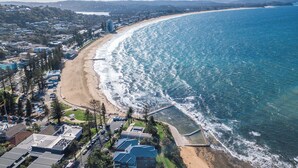 Vista aérea de una zona costera con playa, edificios y muelle.
