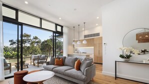 Una sala de estar moderna con un sofá gris, una mesa de centro de madera y un ventanal grande.