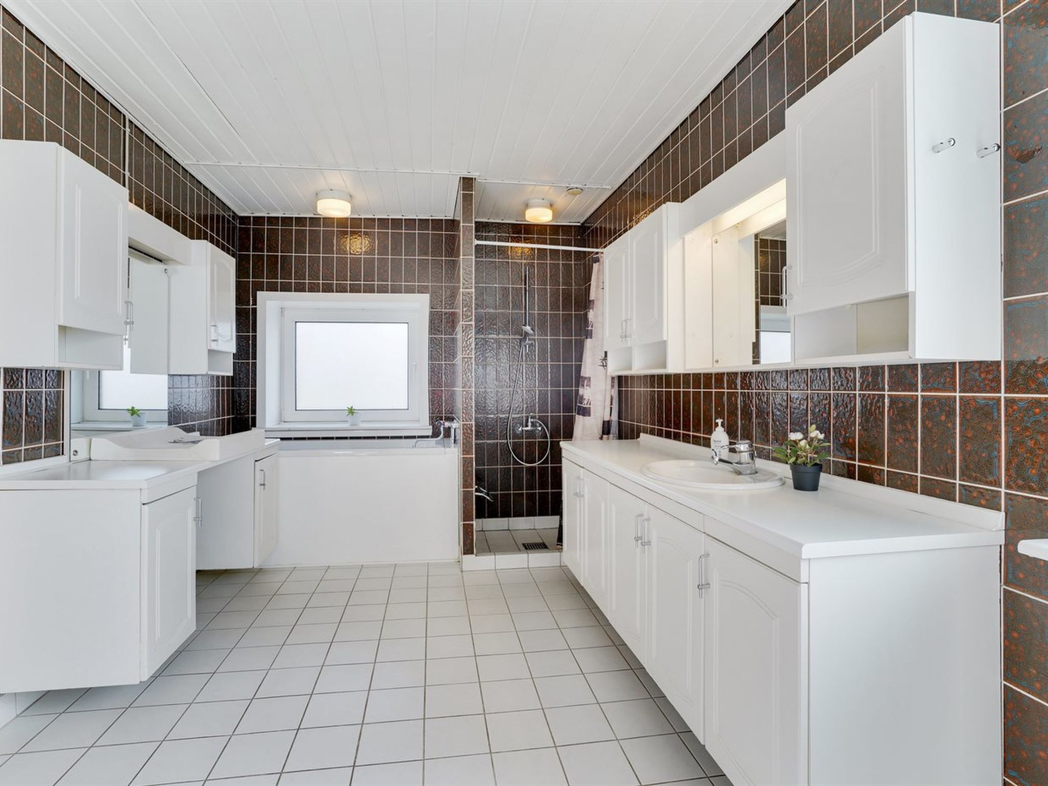Une salle de bain moderne avec des meubles blancs, un grand miroir et un espace douche.