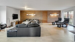 A modern living room with a sectional sofa, a flat-screen TV, and a brick accent wall. - "Rahild" - 2km to the fjord by Interhome (Thyholm)