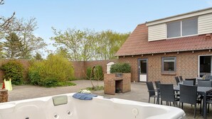 A hot tub in a backyard with a brick house, patio furniture, and a small garden. - "Rahild" - 2km to the fjord by Interhome (Thyholm)