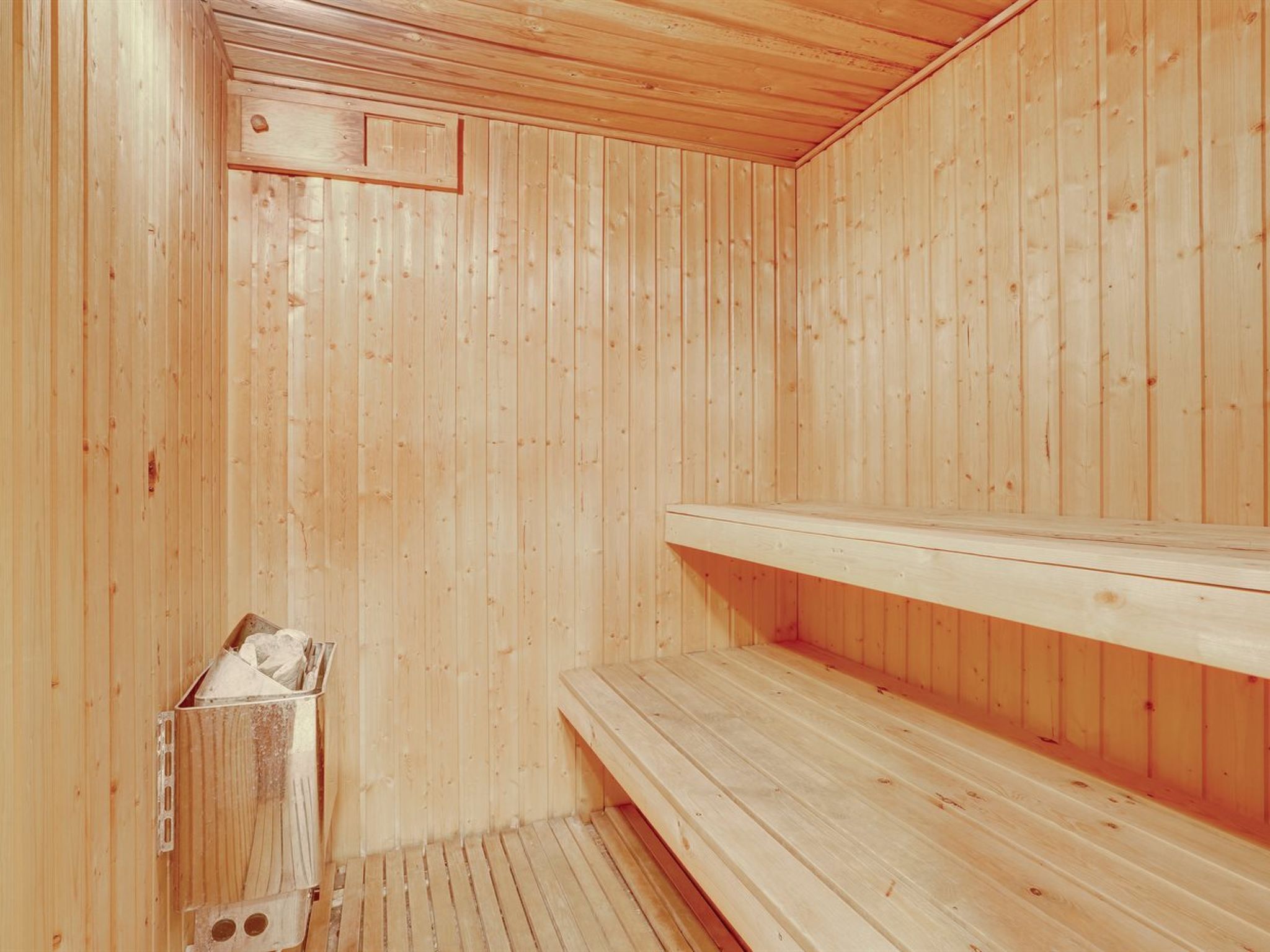 Una sauna de fusta amb bancs i un seient a la caixa.