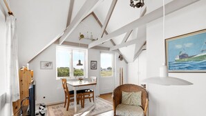 Um quarto acolhedor com uma mesa de jantar de madeira, cadeira de vime e um quadro de um barco na parede.