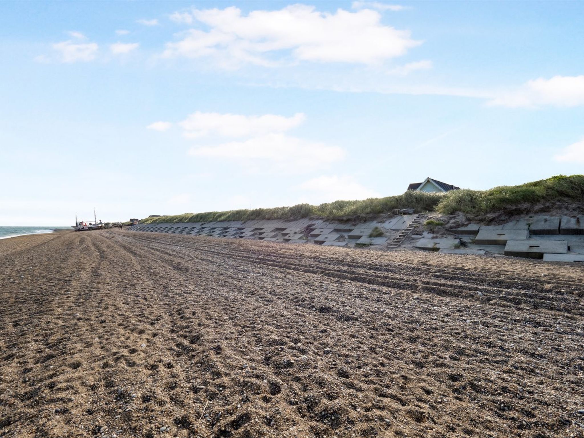 A beach with a concrete retaining wall and steps leading up to a building.