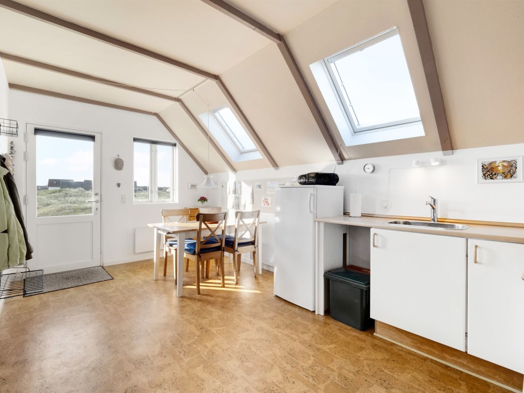 Une cuisine moderne avec un coin repas, des fenêtres de toit et une vue sur l’extérieur.