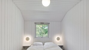 A minimalist room with a bed, two bedside lamps, and a window with a view of trees. - "Henkil" - 700m from the sea by Interhome (Thisted)
