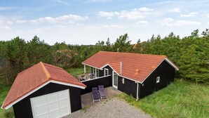 A two-story house with a red-tiled roof, a garage, and a patio with outdoor furniture. - "Henkil" - 700m from the sea by Interhome (Thisted)
