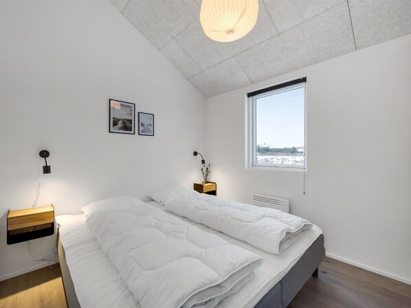 Un dormitorio moderno con una cama grande, una ventana con vistas y decoración sencilla.