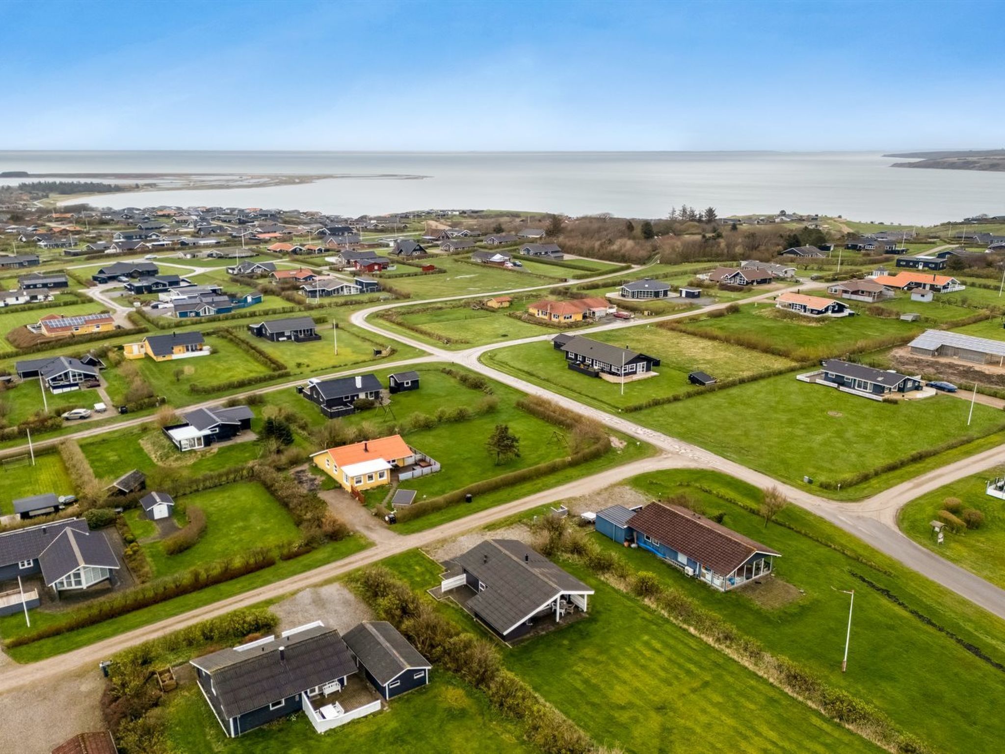 Vista aérea de una zona residencial con casas, carreteras y una gran masa de agua al fondo.