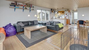 Een ruime woonkamer met houten plafond, een bank, een bijzettafeltje en een eethoek met een houten tafel en stoelen.