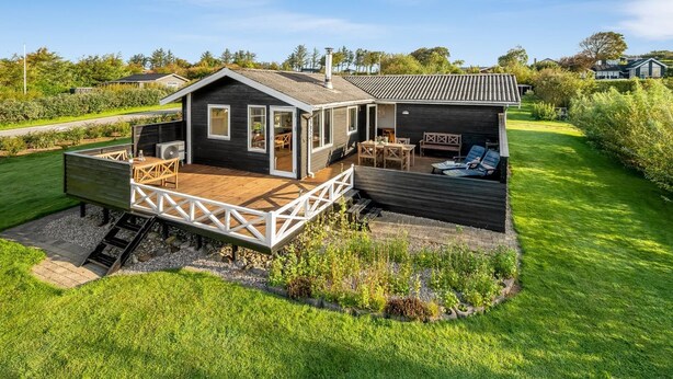 Een modern huis met een houten terras, een overdekte patio en een verzorgde tuin.