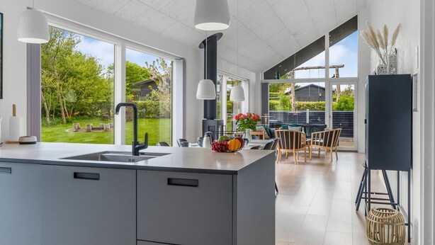 Een moderne keuken met een groot eiland, een eetgedeelte met terras en een uitzicht op de tuin.