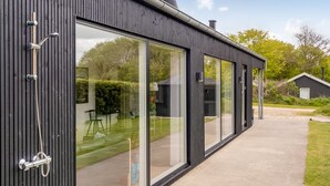 Een modern gebouw met grote glasramen, een metalen dak en een zichtbare schoorsteen.