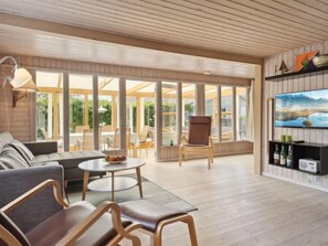 Relax in this open-plan living area with a sofa, coffee table, and chairs, offering views of the outdoors through large windows.