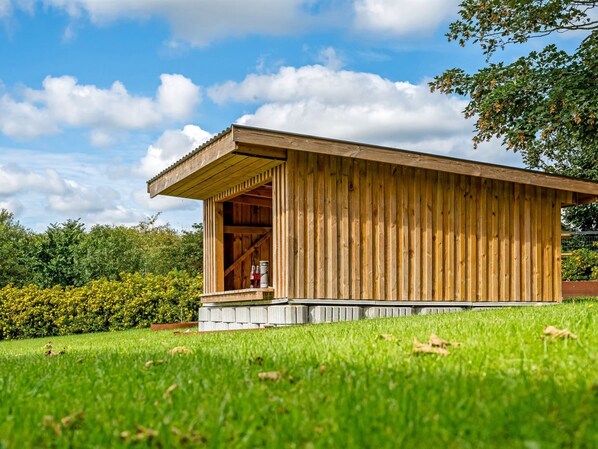 A wooden structure with a sloped roof, a small porch, and a concrete foundation.