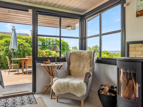 A cozy room with a large window, a fireplace, and a comfortable chair.