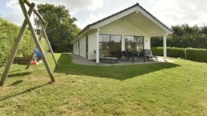 A single-story house with a covered patio, a swing set, and a well-maintained lawn. - "Kyllikki" - 300m to the fjord by Interhome (Børkop)