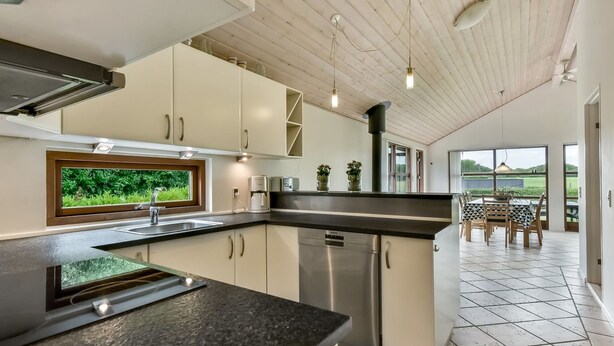 A modern kitchen with a large window, stainless steel appliances, and a dining area with a view. - "Kyllikki" - 300m to the fjord by Interhome (Børkop)