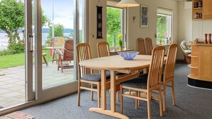 Ein Essbereich mit großem Tisch und Stühlen, einer Hängelampe und Blick ins Freie.