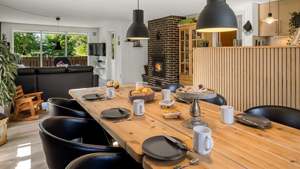 Ein stilvoller Essbereich mit einem Holztisch, gedeckt für vier Personen, schwarzen Stühlen und Pendelleuchten.