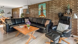 Ein modernes Wohnzimmer mit einem schwarzen Ledersofa, einem Holztisch und einem schwarzen Ledersessel.