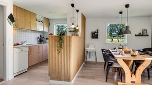 Eine moderne Küche mit Holzausstattung, einer zentralen Kochinsel und Pendelleuchten.