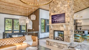 A modern interior with a stone fireplace, leather sofa, and dining area. - Morgan Trail - Hot tub & ping pong table (Blue Ridge Mountains)