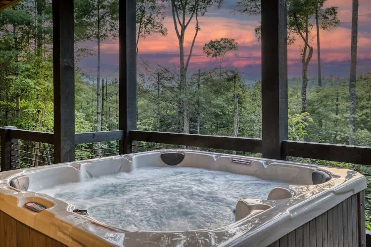 Ein Whirlpool mit Blick auf einen Wald und einen Sonnenuntergang.
