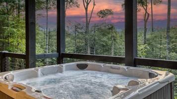 Ein Whirlpool mit Blick auf einen Wald und einen Sonnenuntergang.