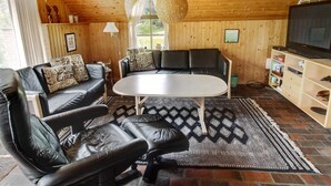 A cozy living room with a black leather sofa, a round coffee table, and a patterned rug. - "Ilva" - 300m to the fjord by Interhome (Ulfborg)