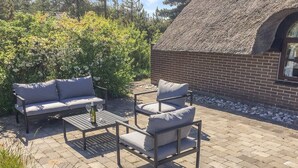 An outdoor patio area with a sofa, armchair, and table set up. - "Ilva" - 300m to the fjord by Interhome (Ulfborg)