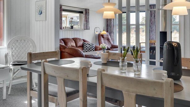 Ein modernes Wohnzimmer mit einem runden Holztisch, einer Ledersofa und einem großen Fenster mit Vorhängen.