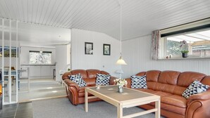 Ein modernes Wohnzimmer mit Ledersofas, einem Holztisch und einem Essbereich.