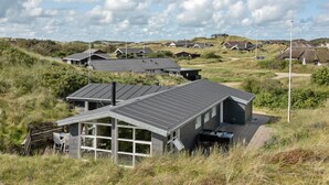 A modern building with a sloped roof, large windows, and a covered outdoor seating area. - "Jess" -  from the sea by Interhome (Ringkøbing)