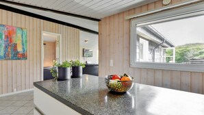 A modern kitchen with wooden paneling, a granite countertop, potted plants, and a fruit bowl. - "Jess" -  from the sea by Interhome (Ringkøbing)
