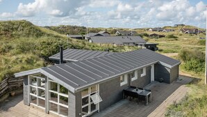 A modern house with a flat roof, large windows, and a patio area. - "Jess" -  from the sea by Interhome (Ringkøbing)