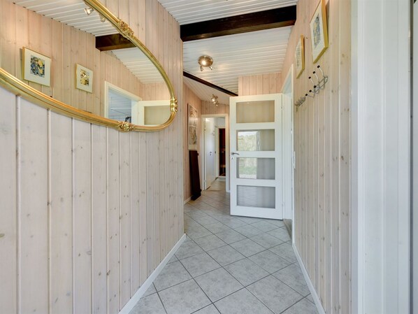 A hallway with wooden paneling, a large mirror, and a door with frosted glass panels.
