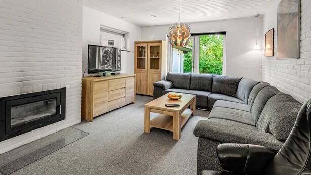 Un salon moderne avec une cheminée, un meuble en bois, un canapé gris et un téléviseur.