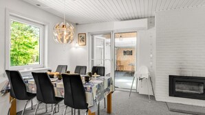Un espace de salle à manger moderne, avec une table dressée pour six personnes, des chaises noires et une grande fenêtre donnant sur un paysage verdoyant.
