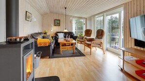 Een gezellige woonkamer met een houtkachel, een leren bank en houten vloeren.