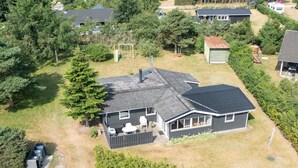 Een gelijkvloers huis met omheinde achtertuin, een terras met tuinmeubilair en een grote boom.