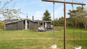 Een huis met een overdekte veranda, een schommel en een gazon.